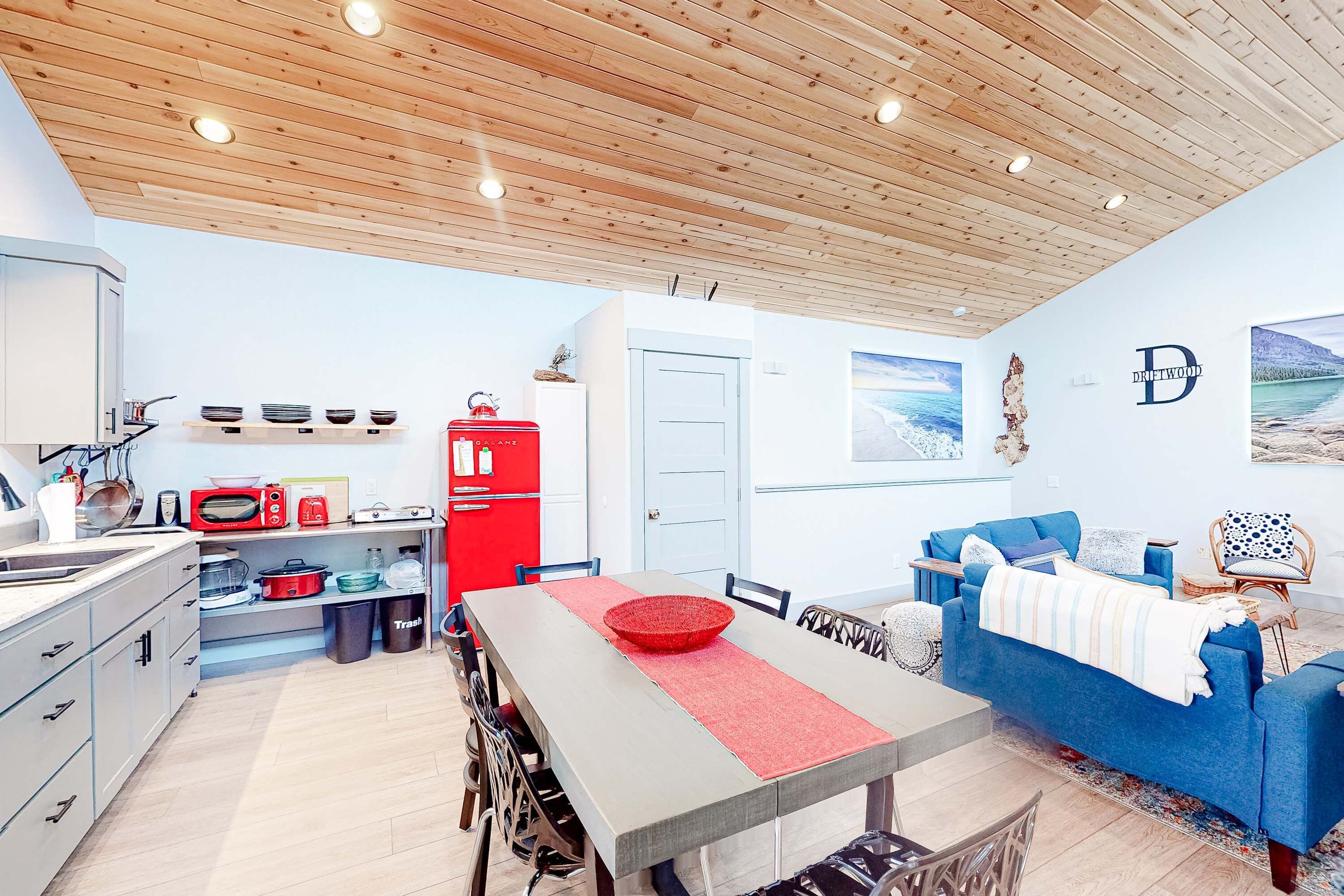 Una cocina moderna con comedor, un refrigerador rojo y un sofá azul.