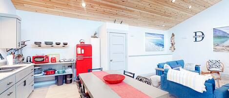 Una cocina moderna con comedor, un refrigerador rojo y un sofá azul.