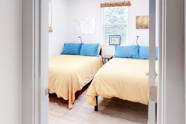 A room with two beds, a window with a view, and a door.