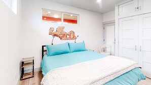 A bedroom with a bed, a wooden nightstand, a white wardrobe, and a window with blinds. - Beachy, Dog-Friendly Home Near the Coast with Free WiFi & a Kitchenette (Bandon)