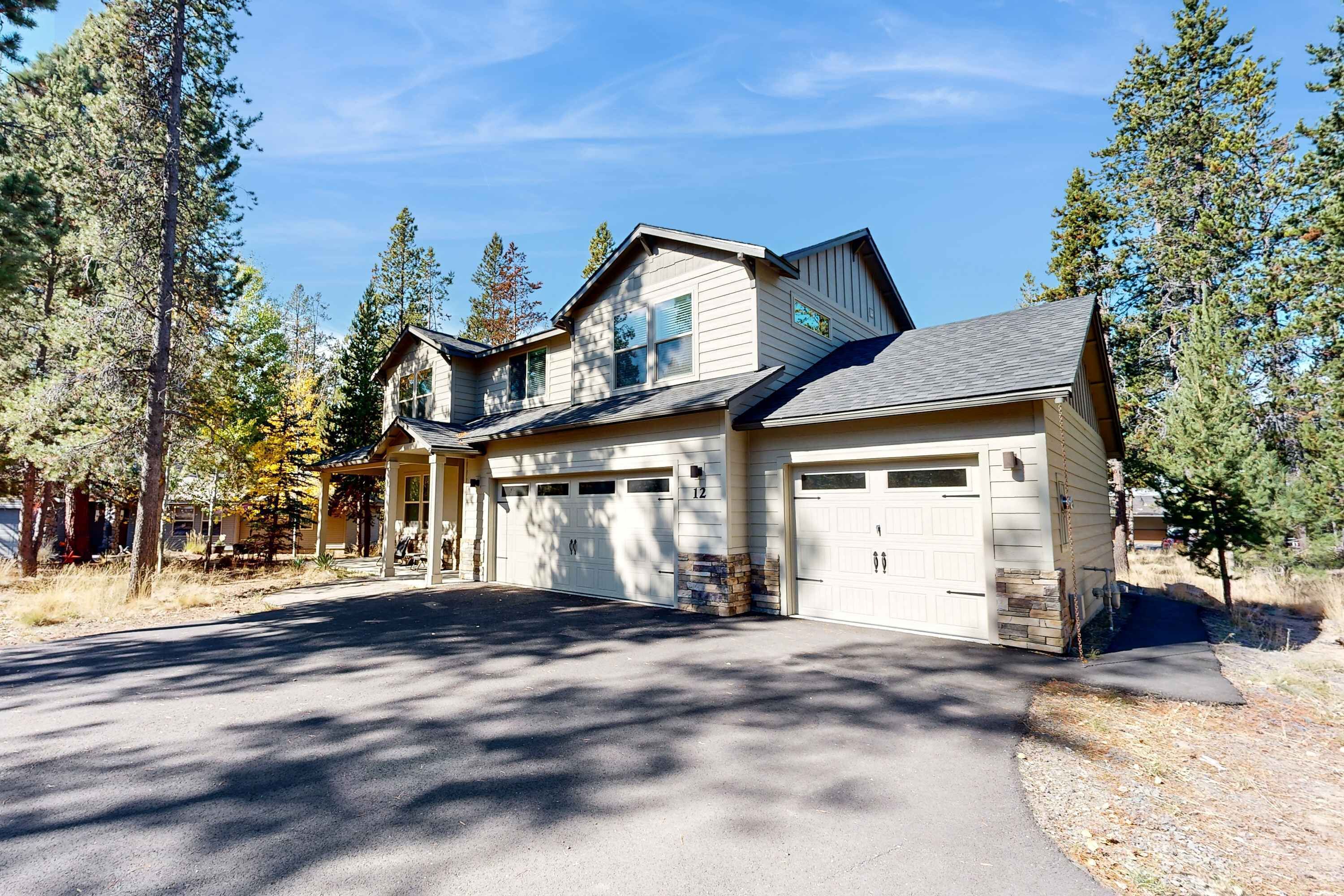 A two-story house with a garage, surrounded by trees.