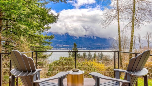 A deck with Adirondack chairs and a table, overlooking a lake and mountains. - Modern, river-view home with 2 decks, Ping-Pong, fireplace & washer/dryer (Stevenson)