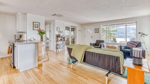 A modern living space with a kitchen, dining area, and a sofa with a view. - Modern, river-view home with 2 decks, Ping-Pong, fireplace & washer/dryer (Stevenson)