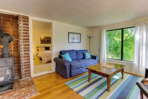 A cozy living room with a sofa, a coffee table, a fireplace, and a large window.