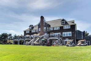 A large building with multiple levels, a prominent chimney, and a covered outdoor seating area with umbrellas.