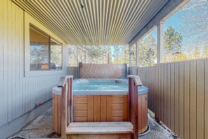 Een hottub met houten panelen, een overdekt terras en een houten hek.