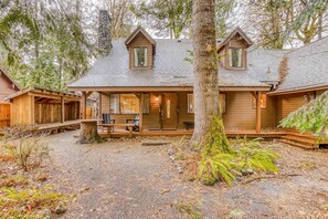 En rustik hytte med veranda, en stenpejs og en træterrasse.