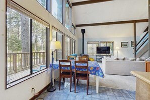 Ein Wohnzimmer mit einer Couch, zwei Holzstühlen, einem Tisch und einem Fernseher.
