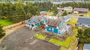 A residential area with houses, a large open driveway, and a fenced yard. - Dog-friendly cottage with pool table, fast WiFi, fireplace, W/D - walk to beach (Long Beach)