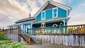 A two-story house with a porch, wooden fence, and a staircase leading to the entrance. - Dog-friendly cottage with pool table, fast WiFi, fireplace, W/D - walk to beach (Long Beach)