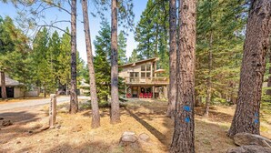 A two-story cabin with a deck, surrounded by tall pine trees. - House in Black Butte Ranch with shared amenities (Black Butte Ranch)