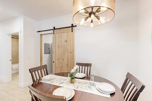 Ein Essbereich mit Holztisch, Stühlen, einer Kristallleuchtre und einer Schiebetür im Scheunenstil.