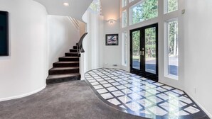 A curved staircase leading to a door with a glass panel, a tiled floor, and a wall-mounted picture. - Stylish & secluded home with a washer&dryer, fireplace, & resort amenity access (Black Butte Ranch)