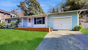 Ein Bungalow mit Garage, kleiner Veranda und gepflegtem Rasen.