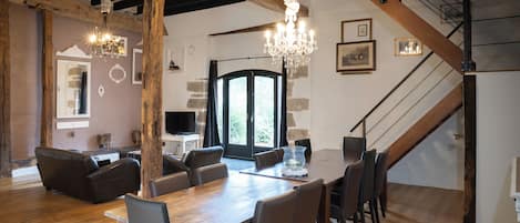 A dining area with a wooden table and chairs, a chandelier, and a staircase.