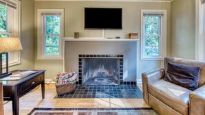 A living room with a fireplace, a television mounted above it, and a leather sofa.