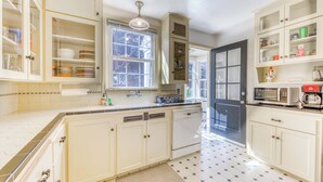 A kitchen with white cabinets, a window, a microwave, and a sink.