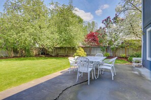 A patio with a table and chairs, a wooden fence, and trees. - Classic & elegant house with entertainment & spacious, laid-back yard (College Place)