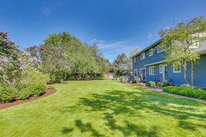 A residential property with a well-maintained lawn, a blue house, and a variety of trees and shrubs. - Classic & elegant house with entertainment & spacious, laid-back yard (College Place)