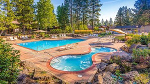 Un espace piscine doté de chaises longues, d’un jacuzzi et entouré d’arbres.