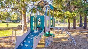 Une aire de jeux avec un toboggan, une zone d’escalade et une structure de jeux couverte.