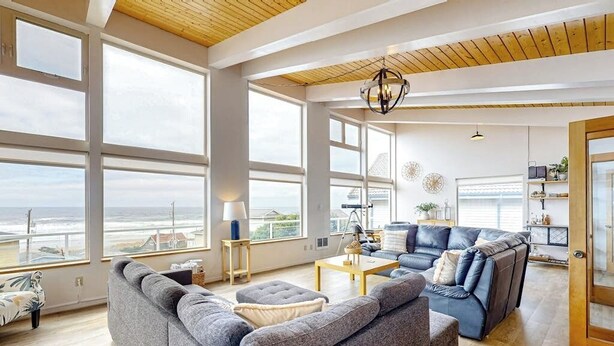 Un salón amplio con ventanas grandes, una lámpara moderna y vista al océano.