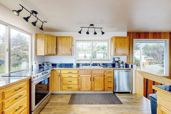 Una cucina con mobili in legno, una lavastoviglie in acciaio inossidabile e un'ampia finestra.