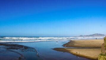 A beach with waves, a sandy shore, and a distant hill.