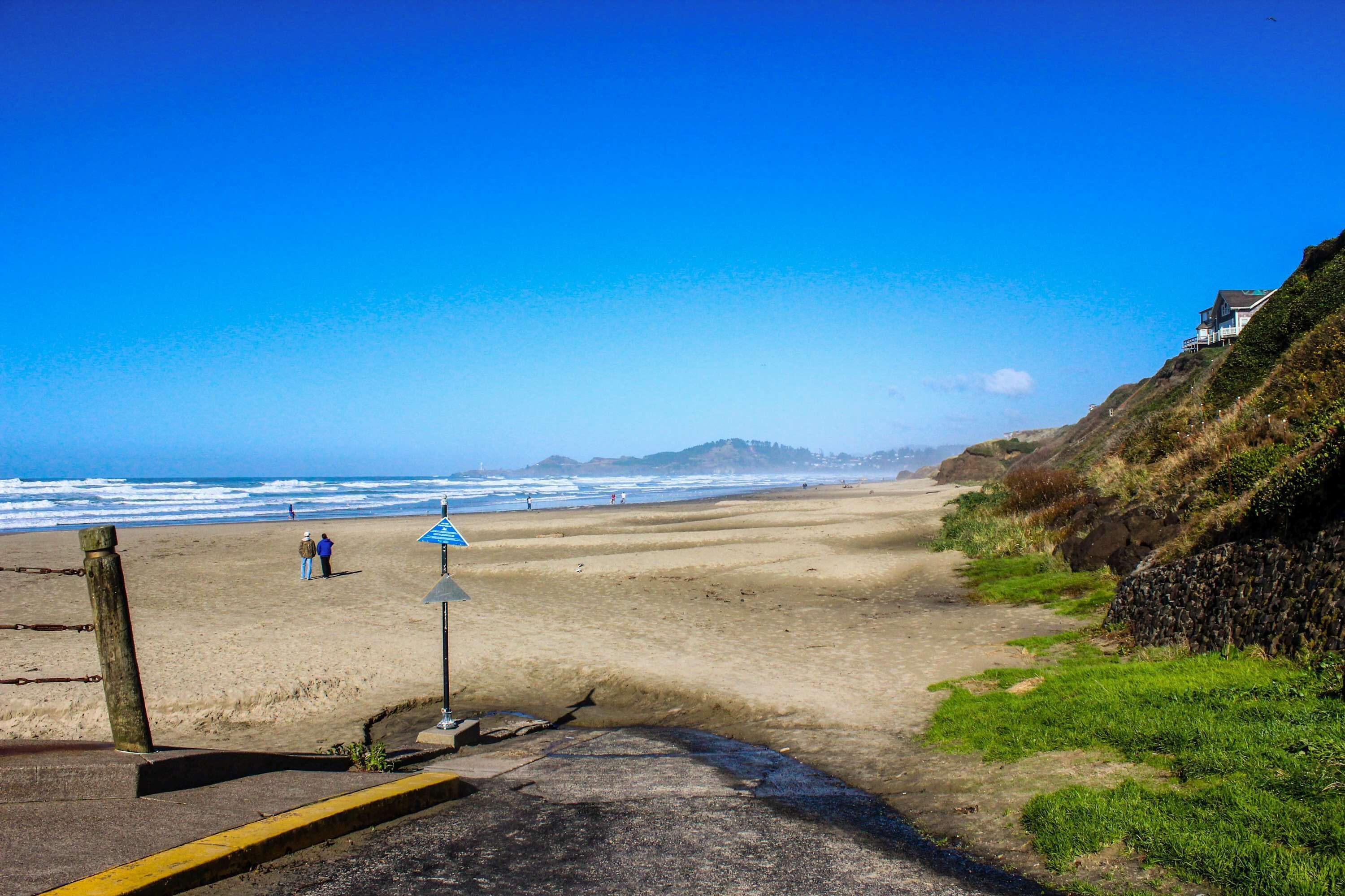 A beach with a clear sky, a sandy shore, and a few people.
