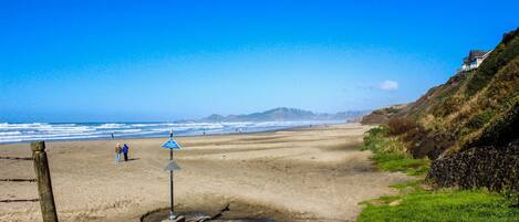 A beach with a clear sky, a sandy shore, and a few people.
