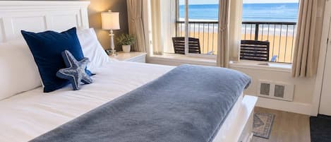 A hotel room with a large bed, a starfish decoration, a lamp, and a view of the beach.