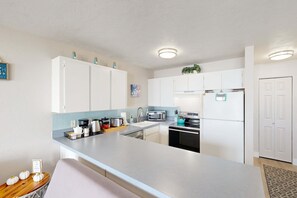 Eine moderne Küche mit weißen Schränken, einem Edelstahlkühlschrank, einer Mikrowelle und einem Spülbecken.