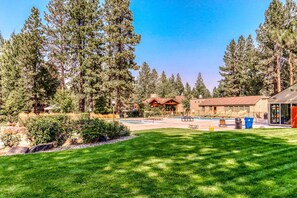 A pool area with a gazebo, a building with a red roof, and a large lawn.