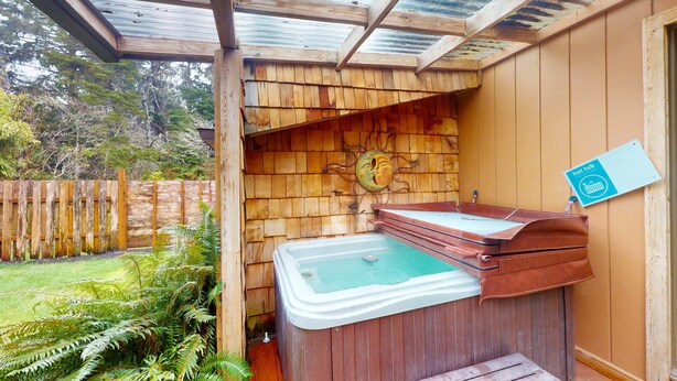 Una vasca idromassaggio con rivestimento in legno, un pontile in legno e una recinzione in legno sullo sfondo.