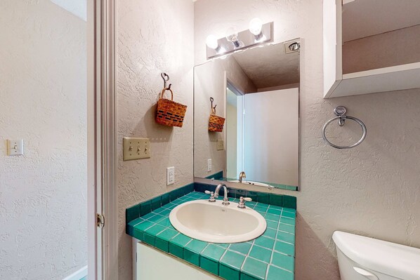 Un baño con lavamanos, espejo e inodoro.