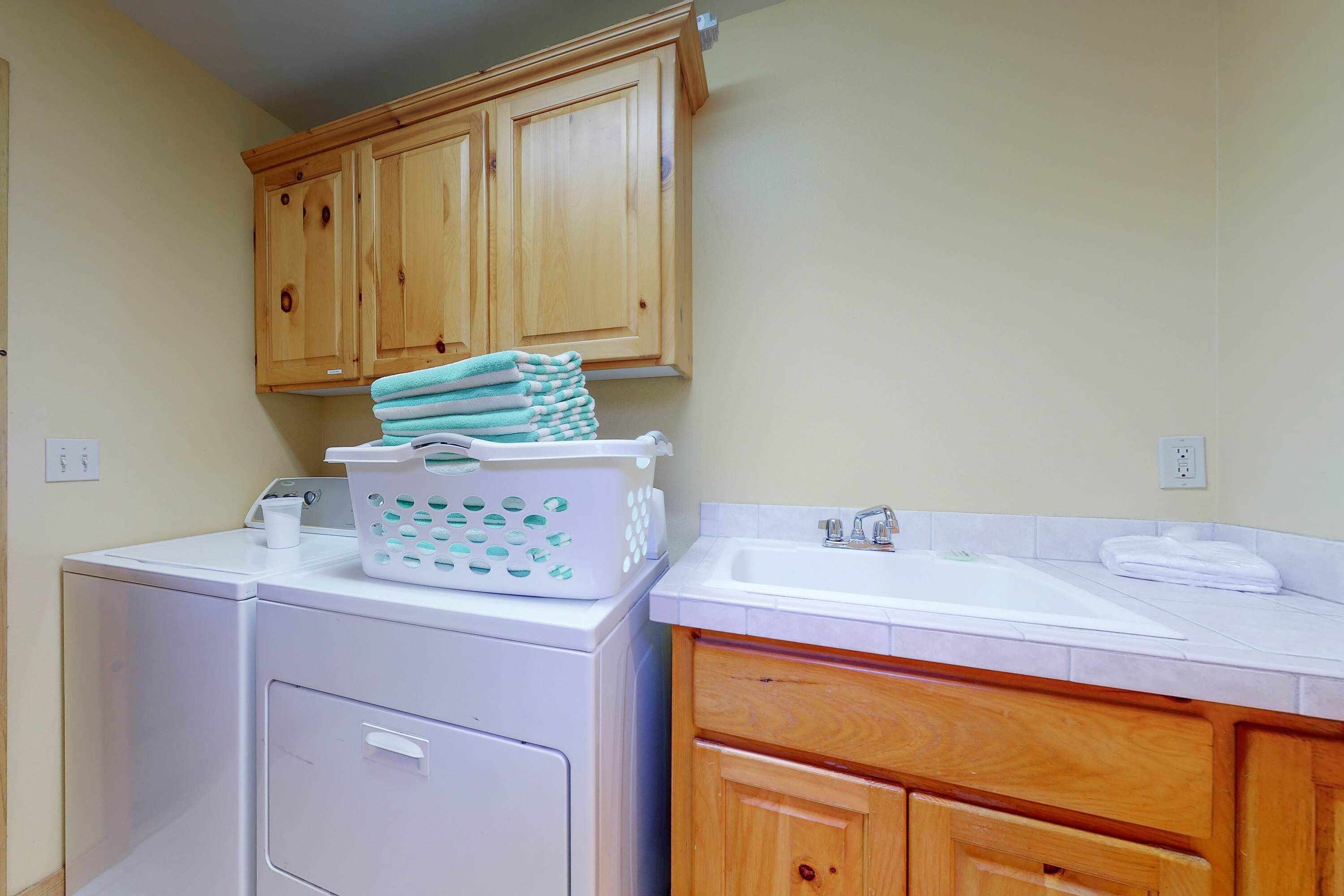 A laundry area with a washing machine, stacked towels, and a laundry basket.