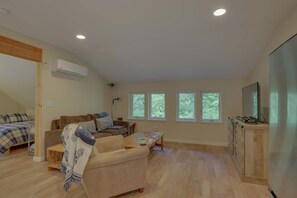 A spacious living area with a sofa, a coffee table, a TV, and a kitchen area with cabinets.