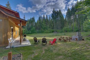 A wooden cabin with a porch, outdoor seating, and a grill area.