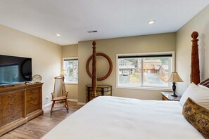 A bedroom with a bed, dresser, TV, chair, lamp, and a large window. - Charming home with ocean views, patio, BBQ grill, WiFi, W&D, walk to beach (Cannon Beach)