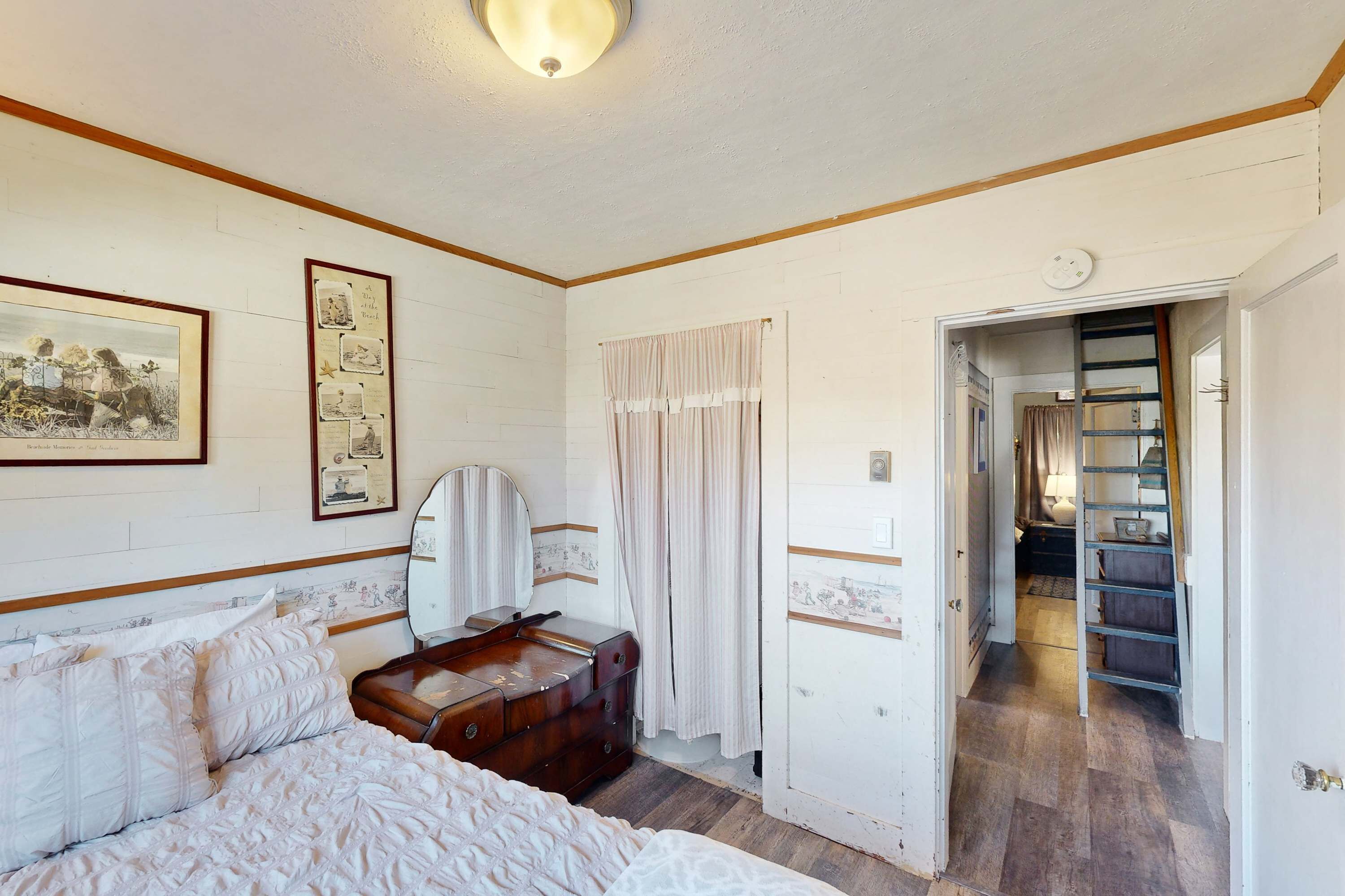 A bedroom with a bed, dresser, mirror, and a door leading to a hallway.