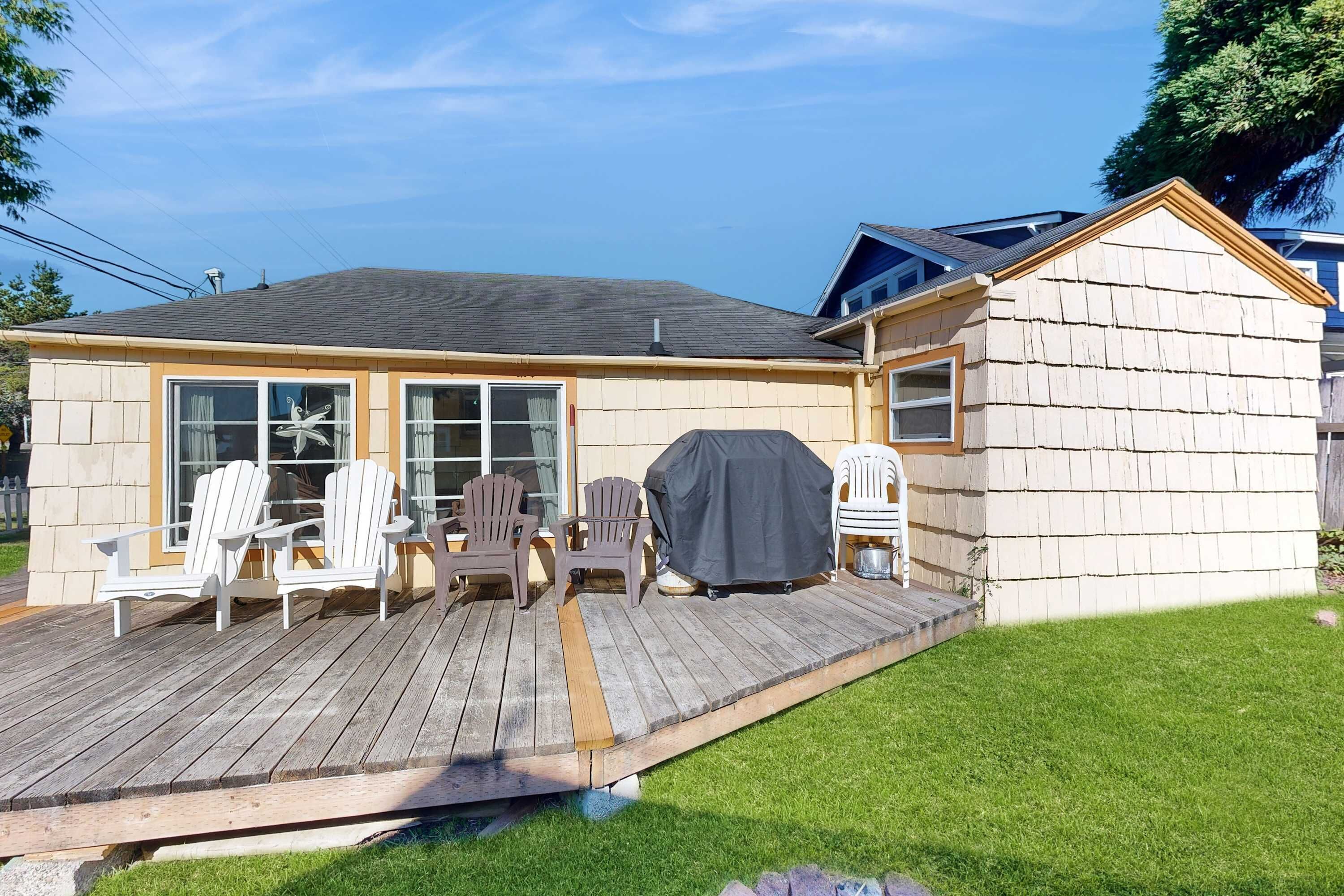 A house with a deck, outdoor seating, and a covered grill area.