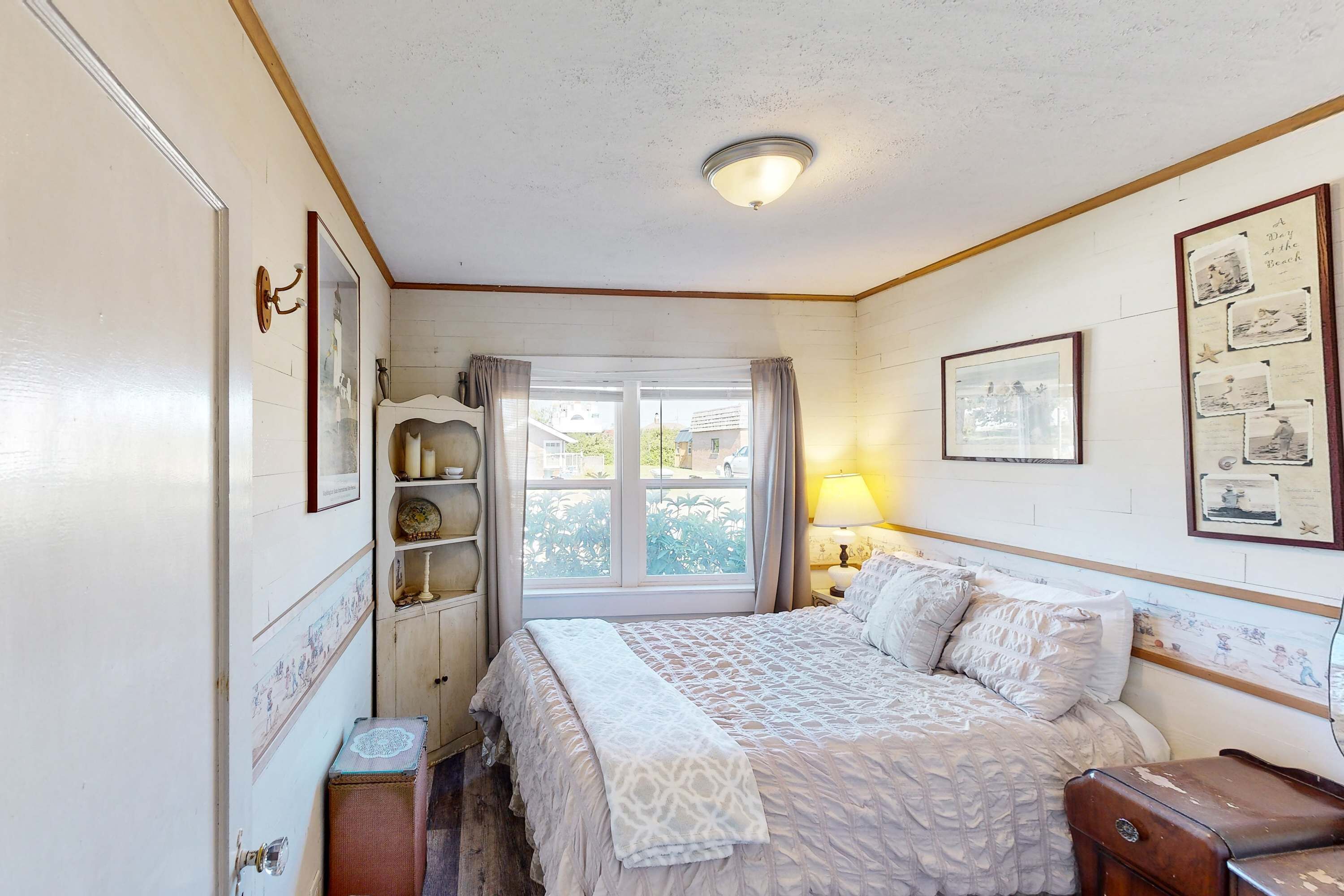 A bedroom with a bed, a window, a lamp, and wall decorations.