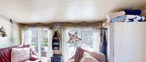 A cozy room with a wooden ceiling, a starfish decoration, a sofa with cushions, and a window with curtains.