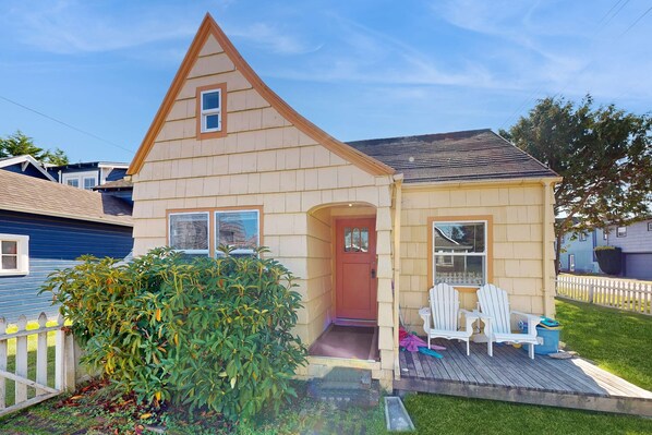 A two-story house with a front porch, a red door, and a small deck with two chairs. - Dog-friendly cottage with fireplace & enclosed yard - walk to beach/eateries (Long Beach)