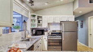 A kitchen with granite countertops, stainless steel appliances, white cabinets, and a window with blinds. - w/ private hot tub & easy access to downtown Bend (Bend)