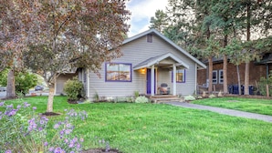 A single-story house with a front porch, a small garden with purple flowers, and a tree in the yard. - w/ private hot tub & easy access to downtown Bend (Bend)