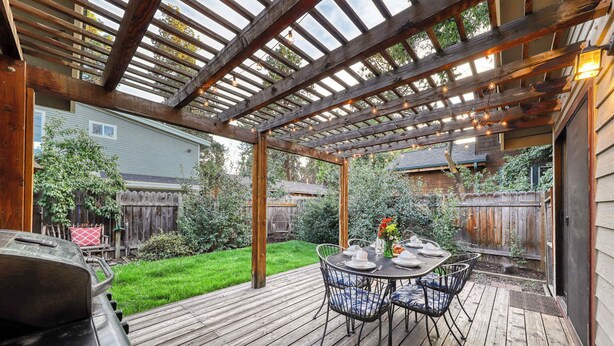 A wooden deck with a pergola, outdoor table and chairs, and a barbecue grill. - w/ private hot tub & easy access to downtown Bend (Bend)