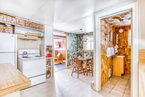 A kitchen with a stove, refrigerator, and wooden dining table.