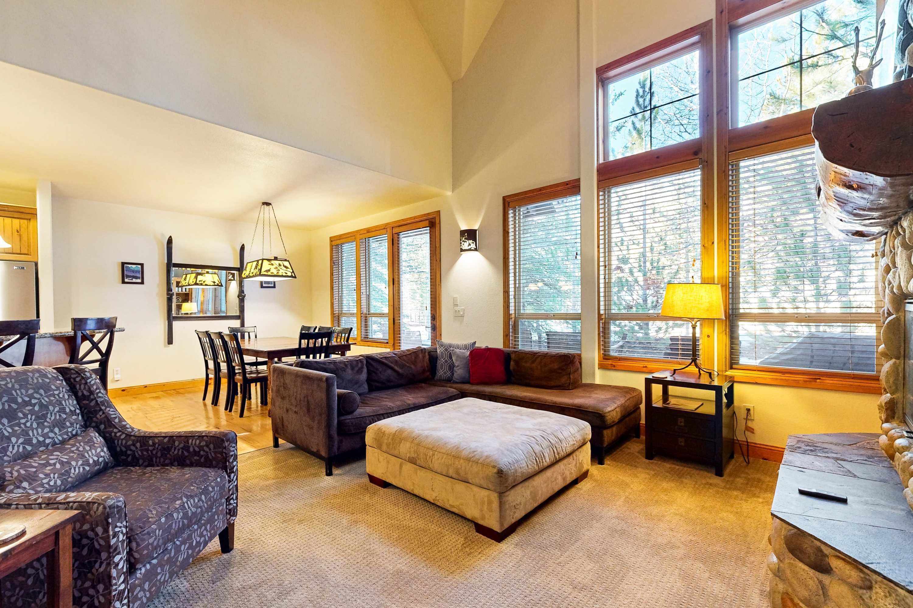 A spacious living room with a sectional sofa, ottoman, and a dining area with a table and chairs.
