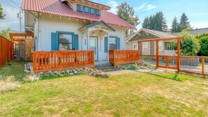 Una casa a due piani con tetto rosso, un portico con ringhiere in legno e un vialetto in pietra che conduce all'ingresso.